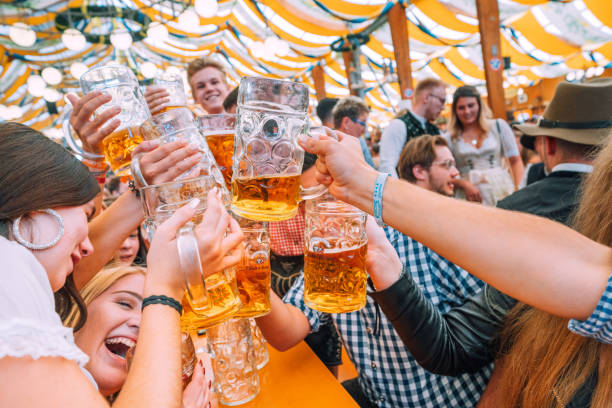 посетители, празднующие октоберфест в пивной палатке, мюнхен, германия - german culture oktoberfest dancing lederhosen стоковые фото и изображения