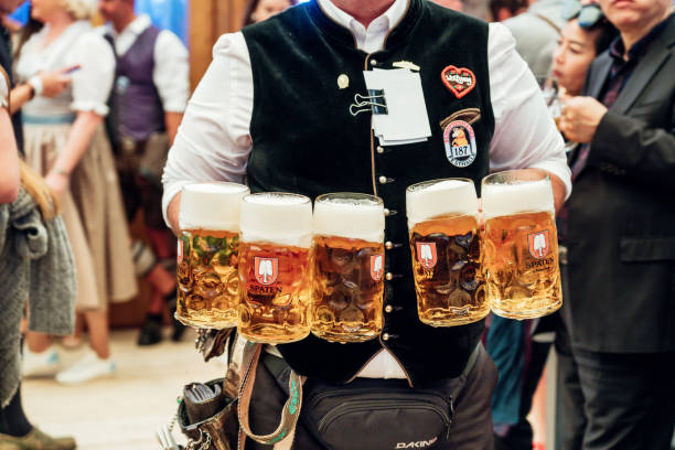 waiter carrying beer glasses at Octoberfest in Munich Munich, Germany - September 21, 2019: waiter carrying a lot of beer glasses in beer garden at Octoberfest in Munich. oktoberfest beer stock pictures, royalty-free photos & images