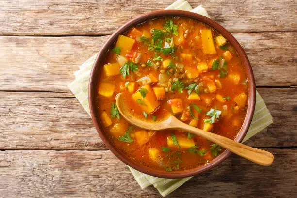 Traditional thick sweet potato soup with lentils close up in a bowl on the table. Horizontal top view from above