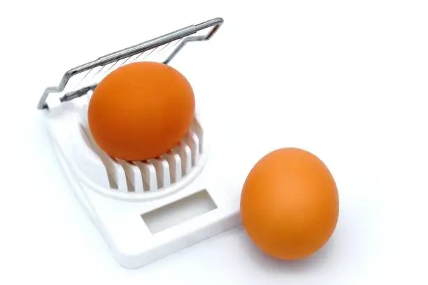 White background, isolate. Crude egg in an egg-cutter. Top view of the cutter with egg.