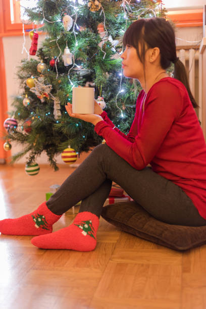 istock Young asian woman decorating christmas tree at home, having coffee break 1178769931