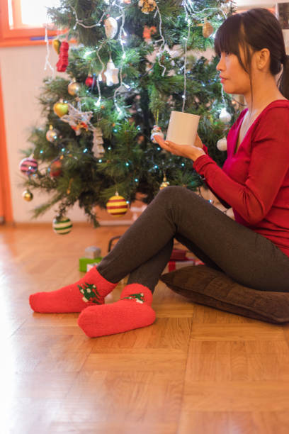 istock Young asian woman decorating christmas tree at home, having coffee break 1178770144