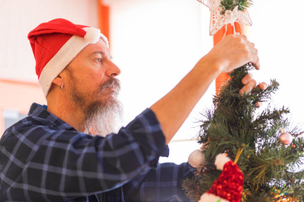 istock Mid aged man wearing santa hat, decorating Christmas tree 1178770837