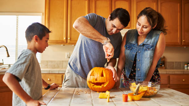 istock halloween activity - family carving pumpkin into jack-o-lantern 1178771846