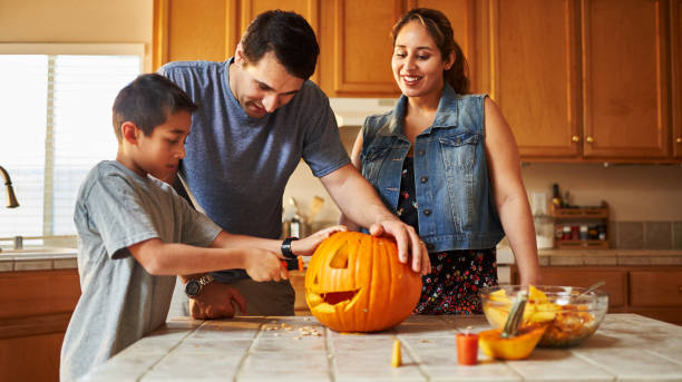 istock halloween activity - family carving pumpkin into jack-o-lantern 1178771892
