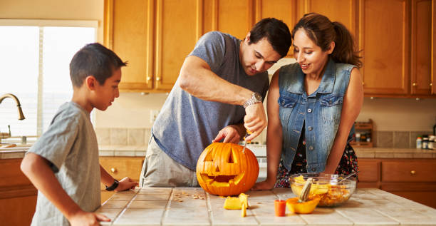 istock halloween activity - family carving pumpkin into jack-o-lantern 1178771905