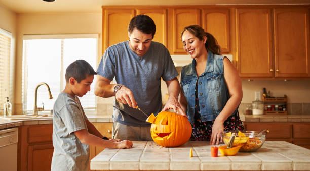 istock halloween activity - family carving pumpkin into jack-o-lantern 1178771907