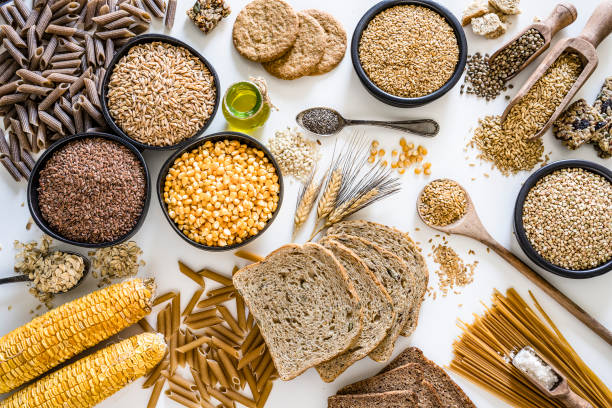 Dietary fiber: large group of wholegrain food shot from above on white background Top view of wholegrain and cereal composition shot on white background. This type of food is rich of fiber and is ideal for dieting. The composition includes wholegrain sliced bread, various kinds of wholegrain pasta, wholegrain crackers, oat flakes, brown rice, spelt and flax seeds. Predominant colors are brown and white. XXXL 42Mp studio photo taken with SONY A7rII and Zeiss Batis 40mm F2.0 CF rice cereal plant photos stock pictures, royalty-free photos & images