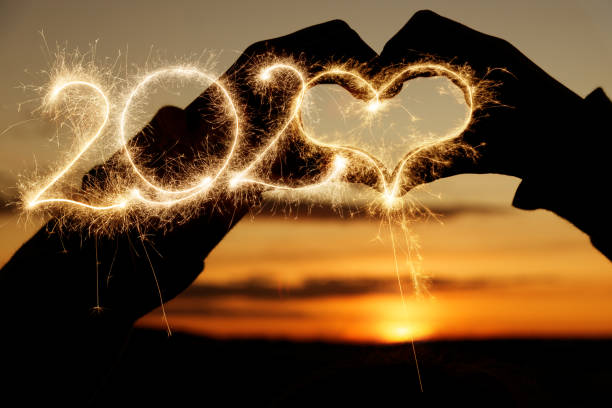 silhueta do coração no por do sol com sparkler 2020 - sparkler sparks new years eve human hand - fotografias e filmes do acervo
