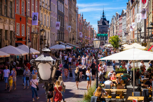 Tourists walk down the street long market visit the old town of Gdansk, Poland. The Golden Gate in background