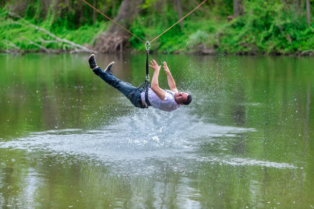 istock young man flying down on zipline over the river, extreme sport 1178778560