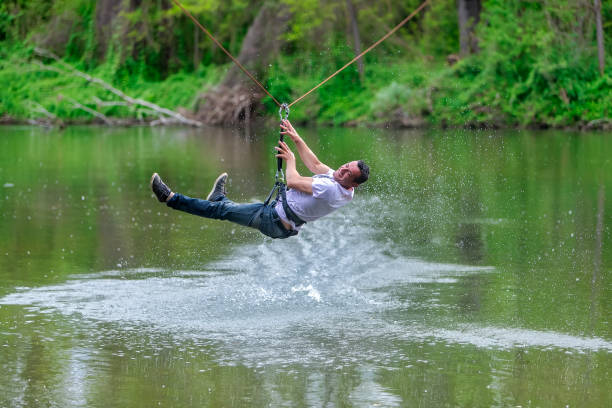 istock young man flying down on zipline over the river, extreme sport 1178778751
