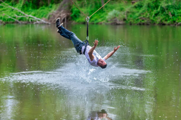 istock young man flying down on zipline over the river, extreme sport 1178778964
