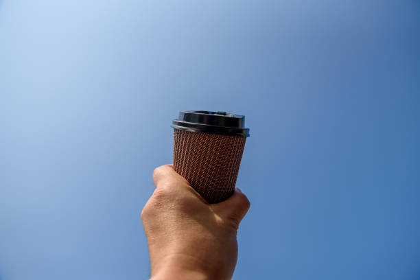 istock Man hand holding paper cup in the blue sky 1178779681