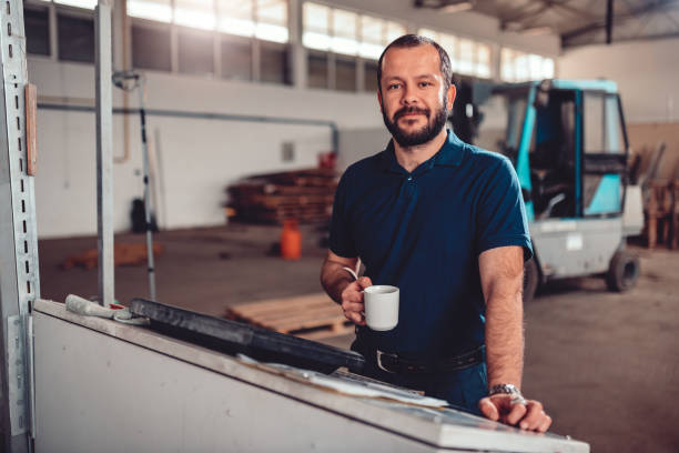 CNC Machine Operator having coffee brake CNC Machine Operator wearing blue shirt having coffee brake in industrial factory menial job stock pictures, royalty-free photos & images