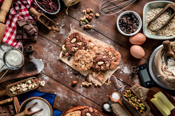 produzione di biscotti al cioccolato e noci su tavolo rustico con scala di peso alimentare digitale.  temi natalizi. - biscotti cookie chocolate pistachio foto e immagini stock