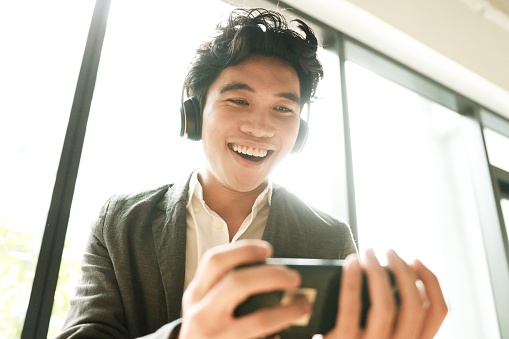 Asian young man is surprising new function on his phone mobile app.