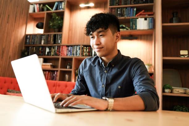 Young asian is working on laptop in the library