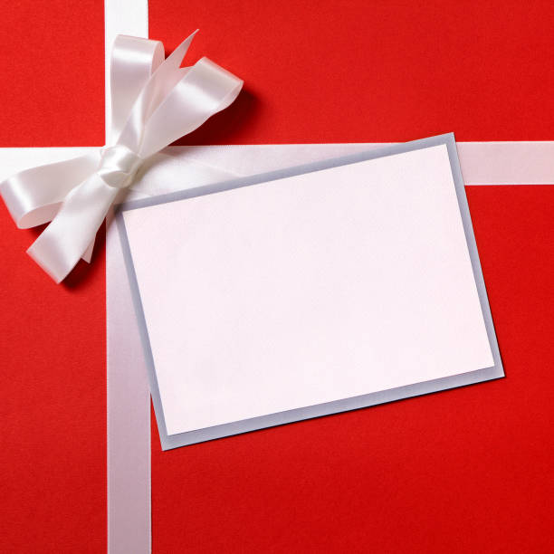 istock Christmas gift card or label and envelope, white ribbon bow, red wrapping paper background, copy space 1178785114