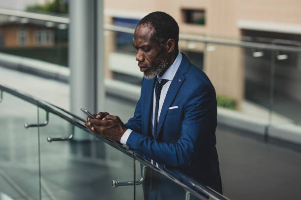 istock African Businessman Standing Outdoors and Typing on a Cell Phone 1178788016