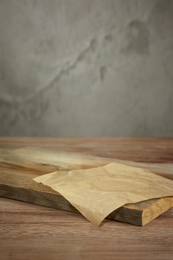 empty cutting board  on table setting in front of a concrete wall