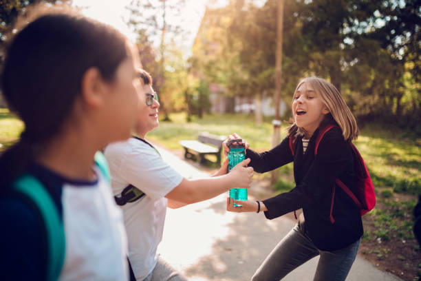 Boy fighting with girl over water bottle at schoolyard Boy fighting with classmate over water bottle at schoolyard schoolyard fight stock pictures, royalty-free photos & images