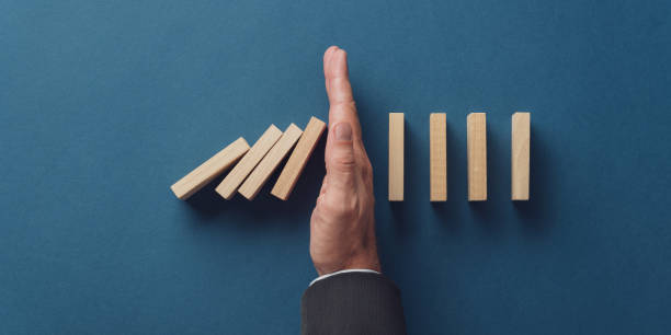 istock Business crisis manager stopping falling dominos from collapsing 1178797272
