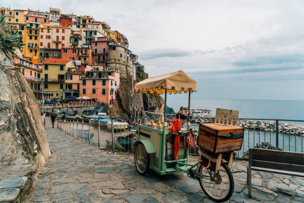 Street food stall in street of Manarola, Cinque Terre, Liguria, Italy View of a street food stall on a bicycle in the street in the coastal old town of Manarola and houses on a hill in the background, Cinque Terre, Liguria, Italy liguria photos stock pictures, royalty-free photos & images
