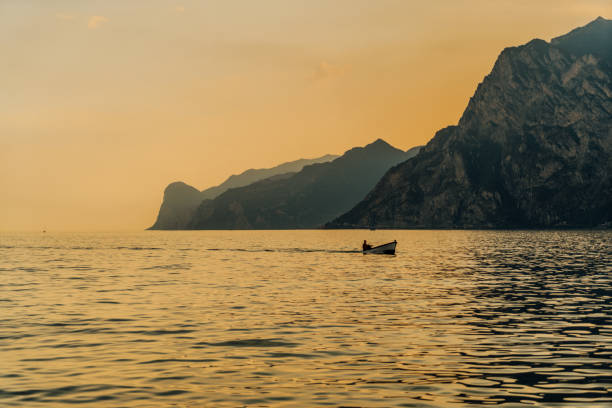 View of sunset over lake and mountain range, Lake Garda, Italy
