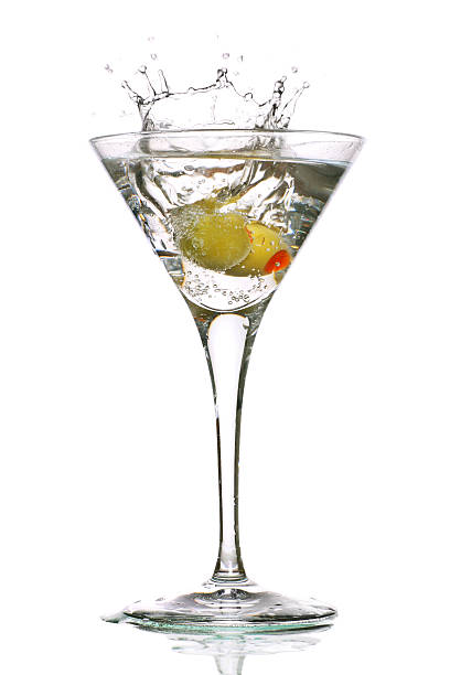 Olive splashing into a clear martini in glass stock photo