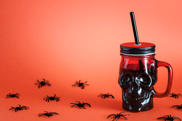 Halloween cocktail in goblet skull on orange background near spiders. Holiday decoration table. Halloween holiday party. Halloween cocktail in goblet skull on orange background near spiders. Holiday decoration table. Halloween holiday party. Copy space for text brain jar stock pictures, royalty-free photos & images