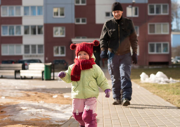 70세의 할아버지가 걷고 있는 2살 짜리 소녀가 산책로에서 야외를 달리고 있습니다. - playground snow winter little girls 뉴스 사진 이미지