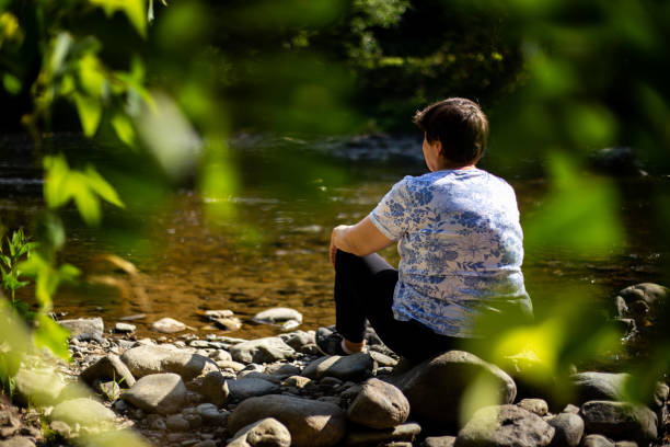 istock Woman sitting and admiring a river in nature 1178807251