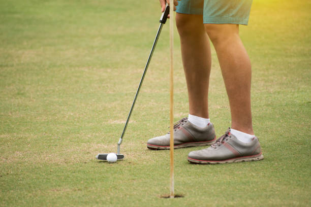 A female golfer focuses on making a fairway shot on a lush golf course, showcasing precision and concentration in her competitive golf attire.