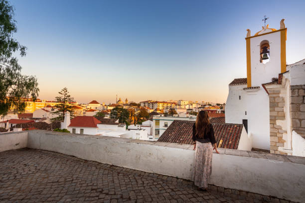 Woman enjoying sunset near Santiago Church (Igreja de Santiago) in Tavira, Portugal stock photo