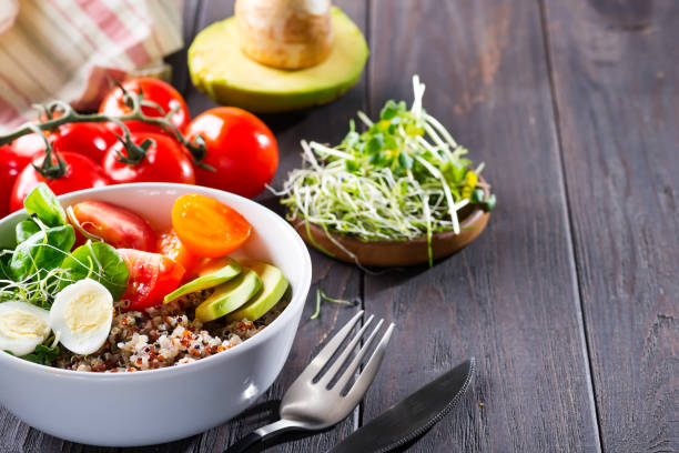 istock Fresh healthy salad with quinoa, cherry tomatoes and mixed greens, avocado, egg and micro greens on wood background top view. Food and health. Superfood meal. Clean eating. Healthy lifestyle 1178817077