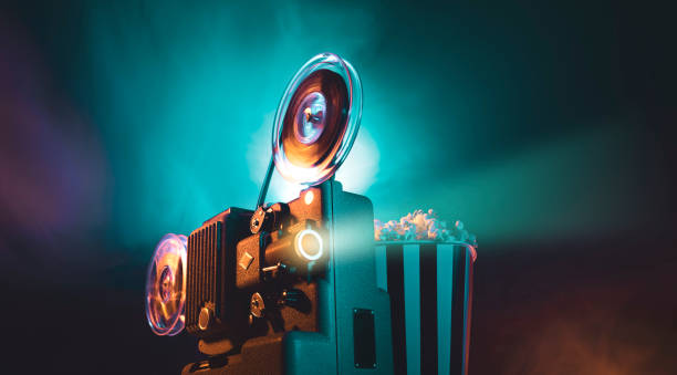 Vintage film projector and film screening Vintage old fashioned projector in a dark room projecting a film, cinematography concept vintage movie projector stock pictures, royalty-free photos & images