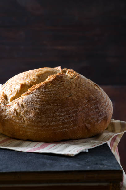istock Round freshly baked rustic rye round bread with wheat ears and napkin on a dark background, copy space 1178820481