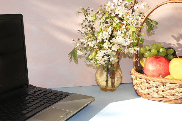 istock Workplace, Computer, flowers and a basket of grapes and apples on a desktop computer sunny table, copy space. 1178821719
