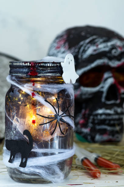 istock Jar filled with orange string lights in spooky room full in a black jar with a web and a spider on a dark background 1178823437