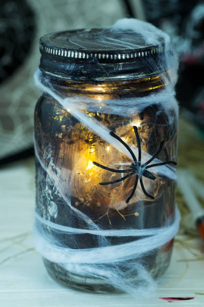 istock Jar filled with orange string lights in spooky room full in a black jar with a web and a spider on a dark background 1178823759