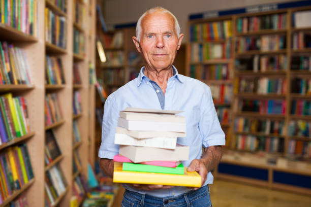 istock Elderly man holding books in bookstore 1178826902