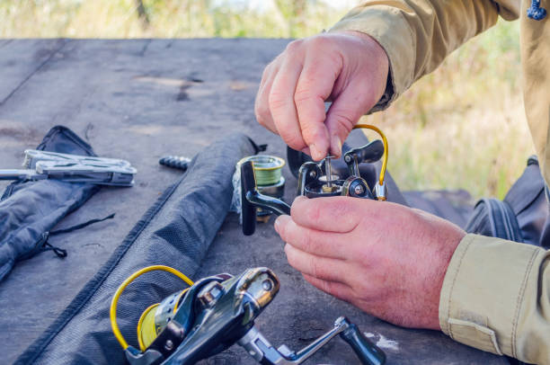 un hombre repara un carrete de pesca con medios improvisados - fishing reel fotografías e imágenes de stock