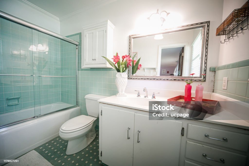 Small outdated tile bathroom with a clear glass door and a white cabinet sink vanity and mirror Small outdated tile bathroom with a clear glass door and a white cabinet sink vanity and mirror. Renovation project. Bathroom Stock Photo