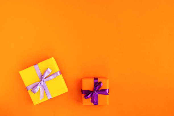 istock Two gift boxes with ribbon and bow on orange background . Top view and space for text. 1178831499