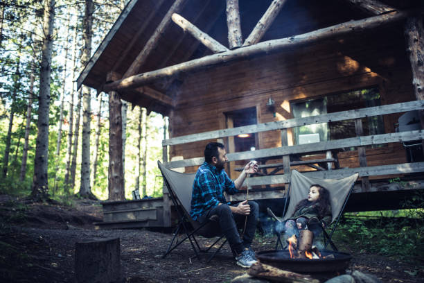 padre e hija cocinando malvaviscos en fogata - wood chair outdoors rural scene fotografías e imágenes de stock