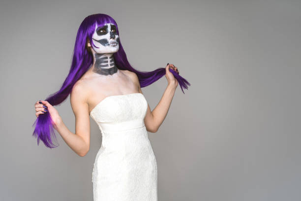 회색 배경 위에 무서운 할로윈 해골 메이크업과 보라색 가발과 웨딩 드레스와 여성의 초상화 - day of the dead mexico bride human skeleton 뉴스 사진 이미지