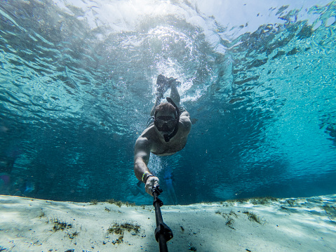 Man takes selfies underwater on crystal clear waters of the Silver Glen park in Florida