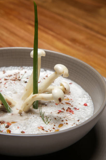 Enoki cream soup in a ceramic bowl, close up. Exquisite dish. Creative restaurant meal. Fine dining concept.