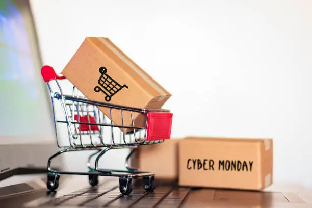 Photo of Carton box and and trolley on laptop computer. Online shopping and Cyber Monday shopping concept